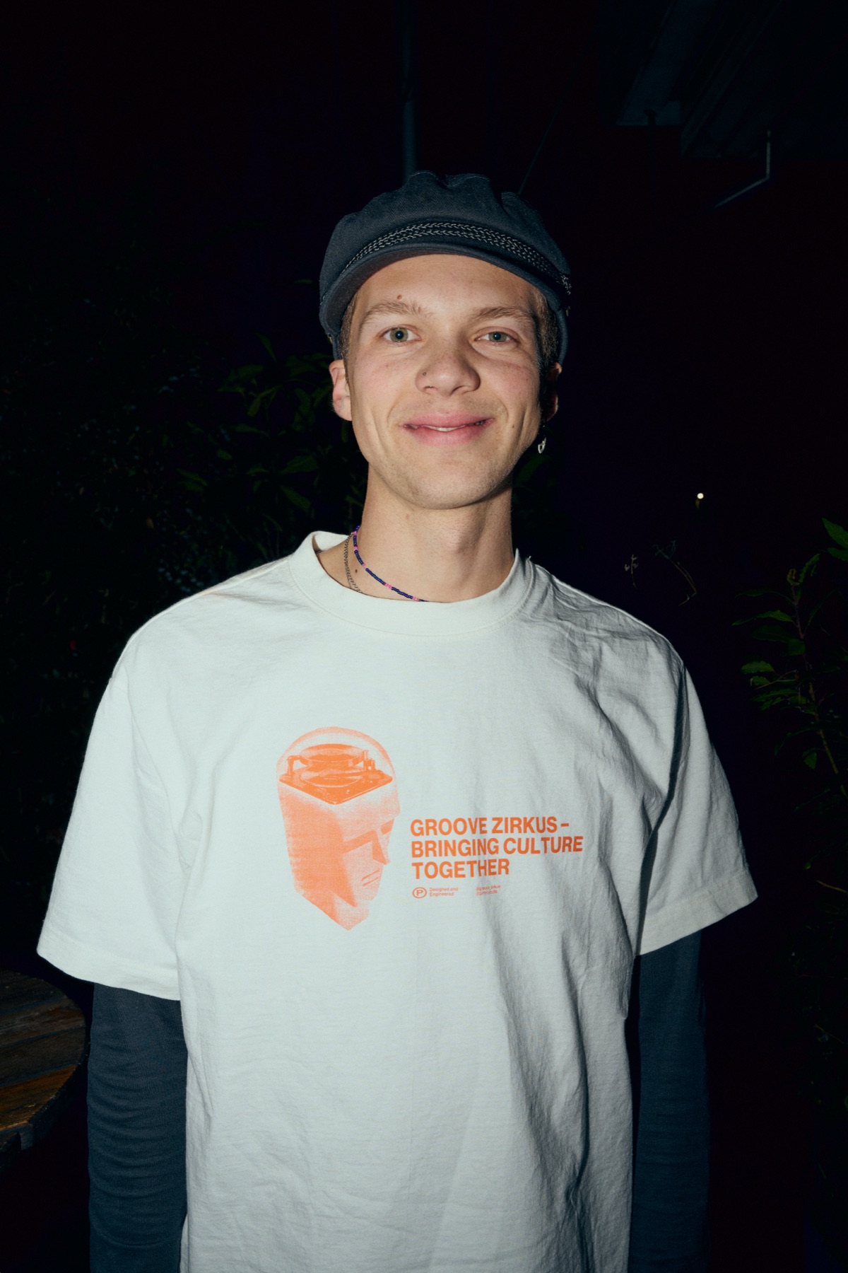 Eliafred mit Cap und weissem T-Shirt vor dunklem Hintergrund